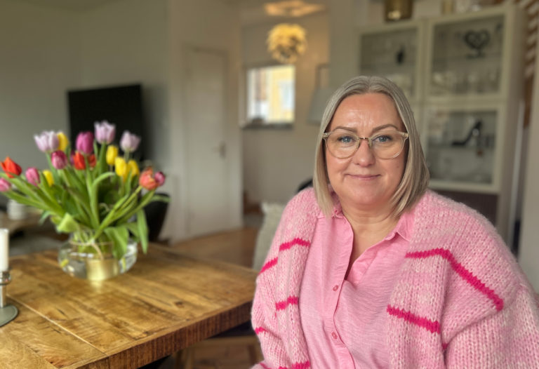 Ett porträtt av Anette där hon sitter hemma vad köksbordet.